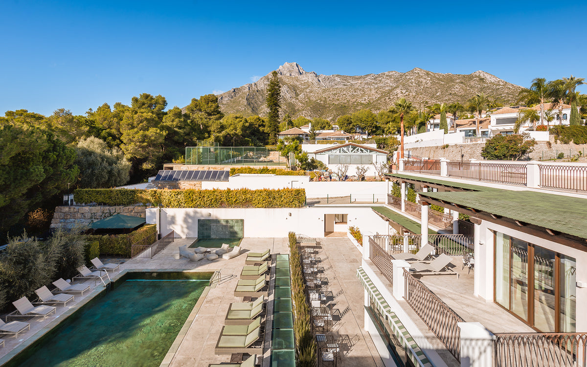Aerial view of the Oasis Premium Recovery residence, its pool and the Sierra Blanca mountains in Marbella